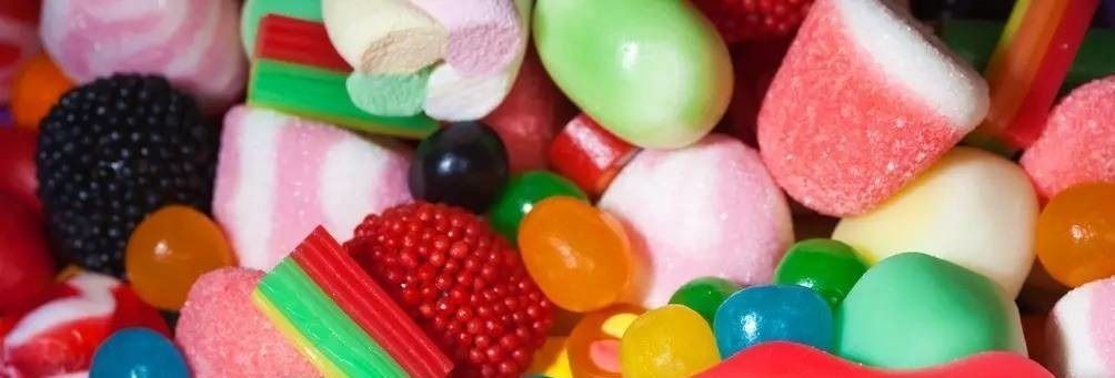 Caramelos y gomitas de colores variados apilados en una vista de cerca.