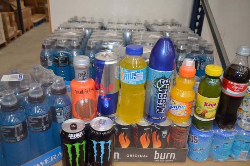 Filas de bebidas embotelladas y bebidas energéticas variadas apiladas en los estantes de la tienda.