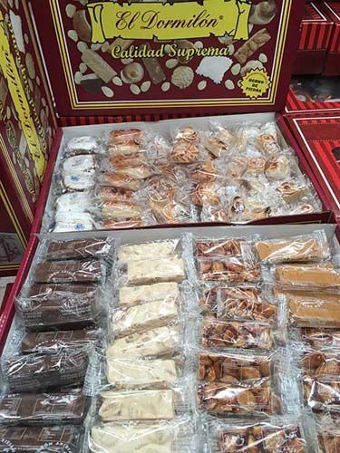 Surtido de dulces y pasteles presentados en una caja de regalo roja con una etiqueta dorada.