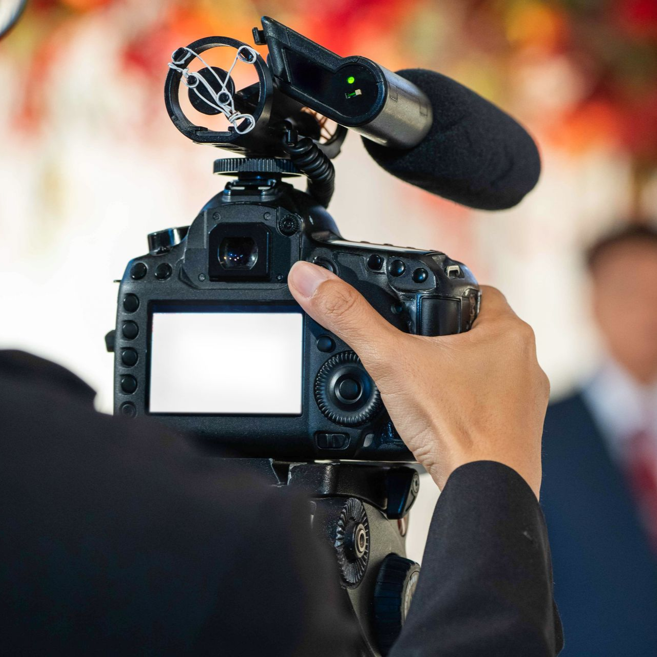 Une personne tenant une caméra avec un microphone, filmant une cérémonie.