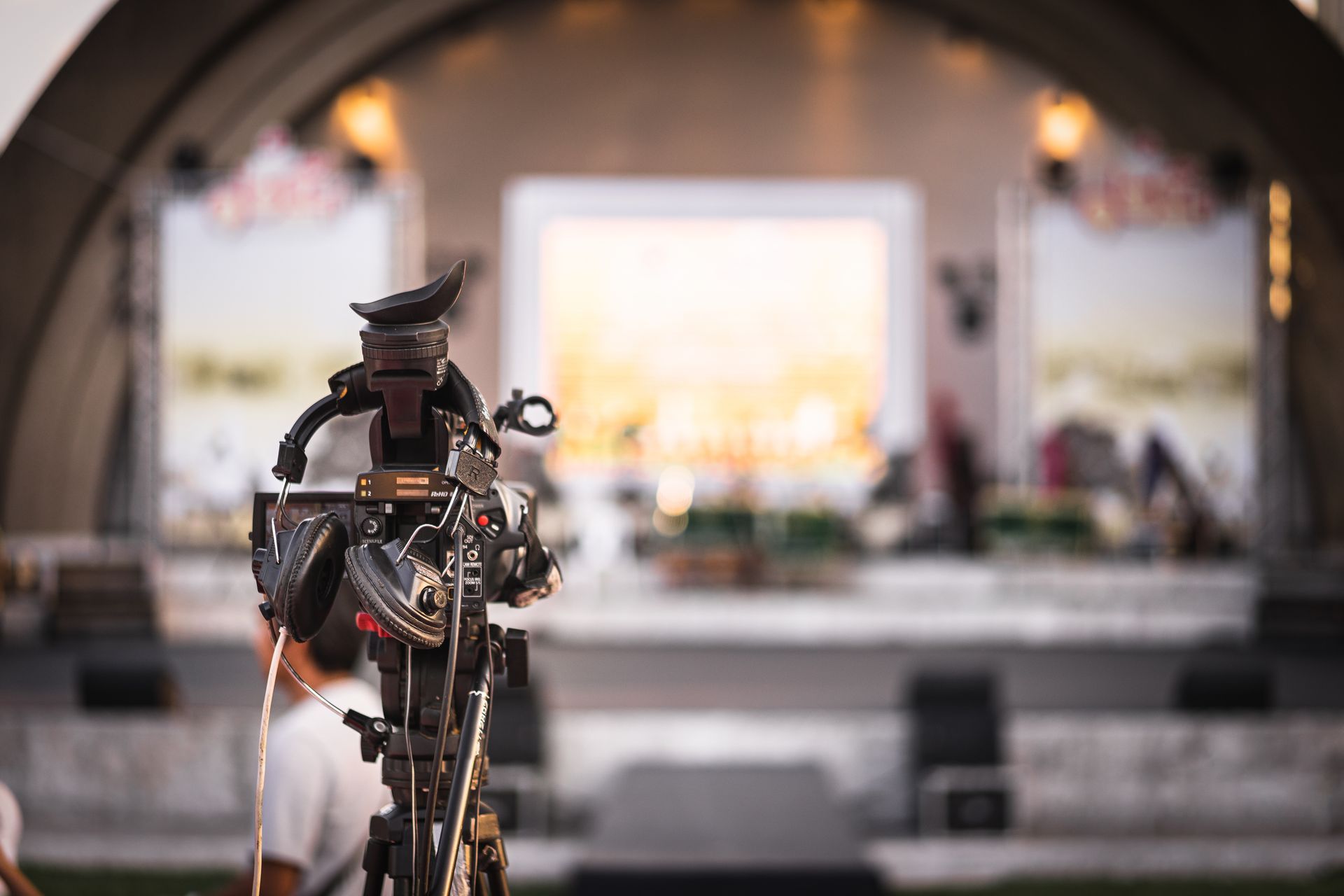 Une caméra sur trépied fait face à une scène éclairée avec un décor.