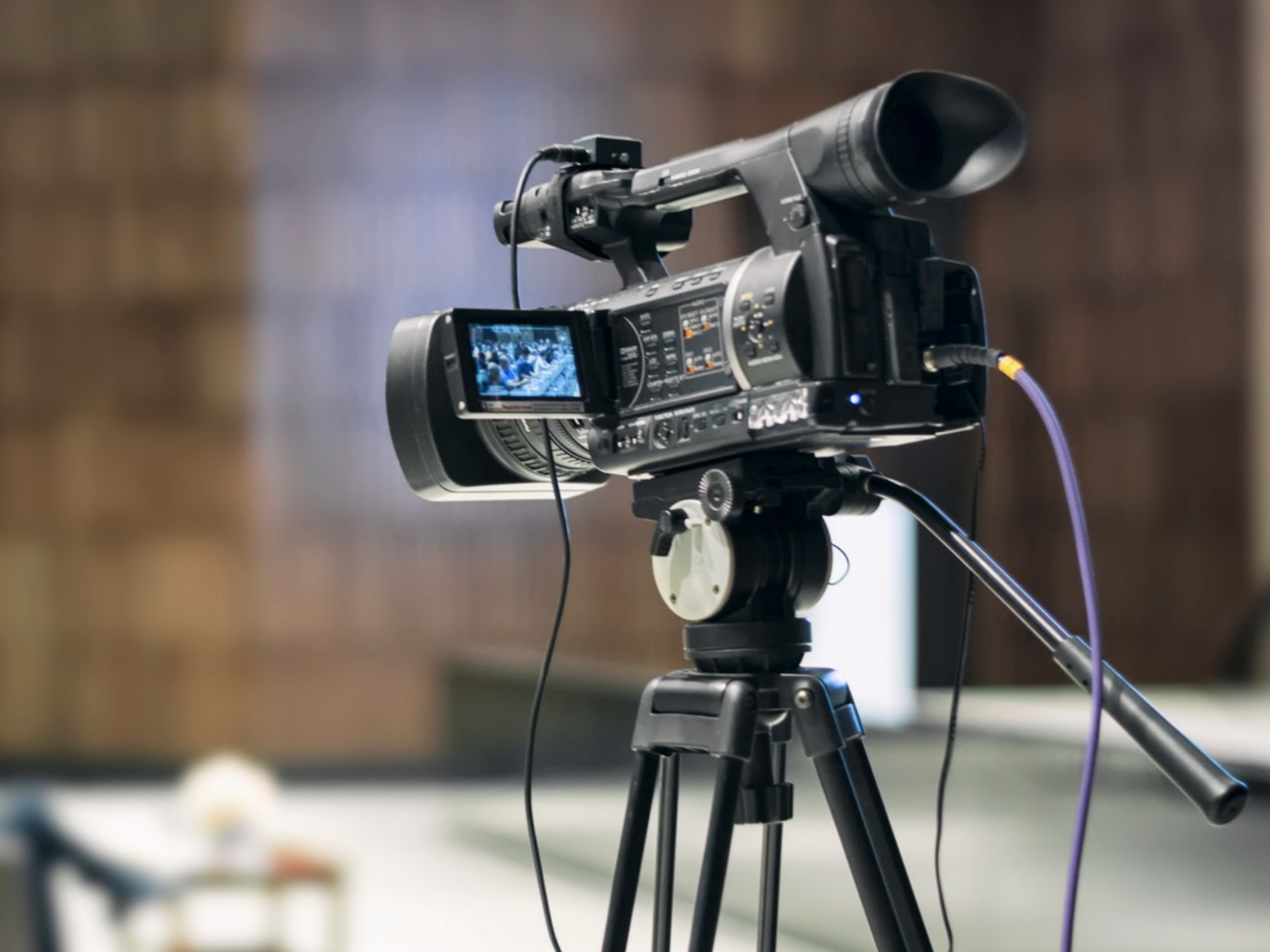 Caméra vidéo sur trépied, enregistrant un arrière-plan flou.