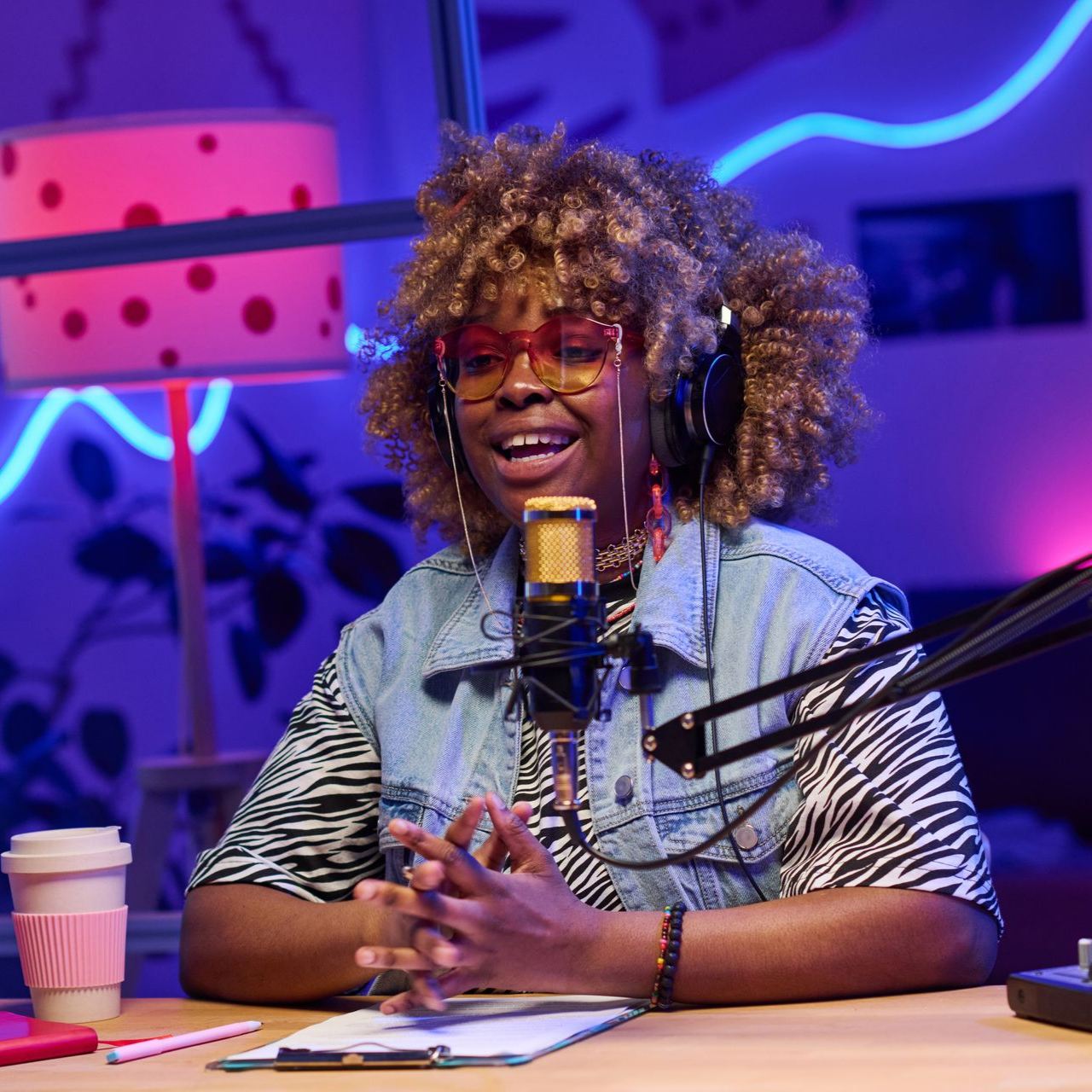 Femme avec un casque audio devant un microphone, dans un studio très éclairé.