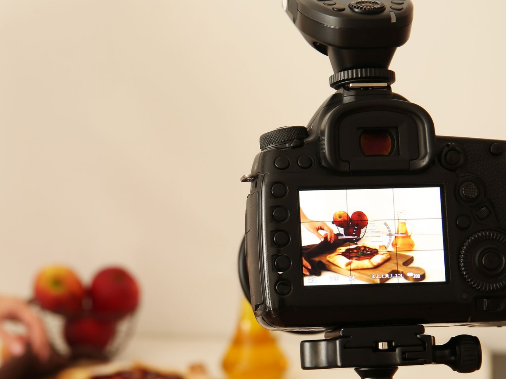 Appareil photo photographiant une composition culinaire avec des pommes, une bouteille et une planche à découper.