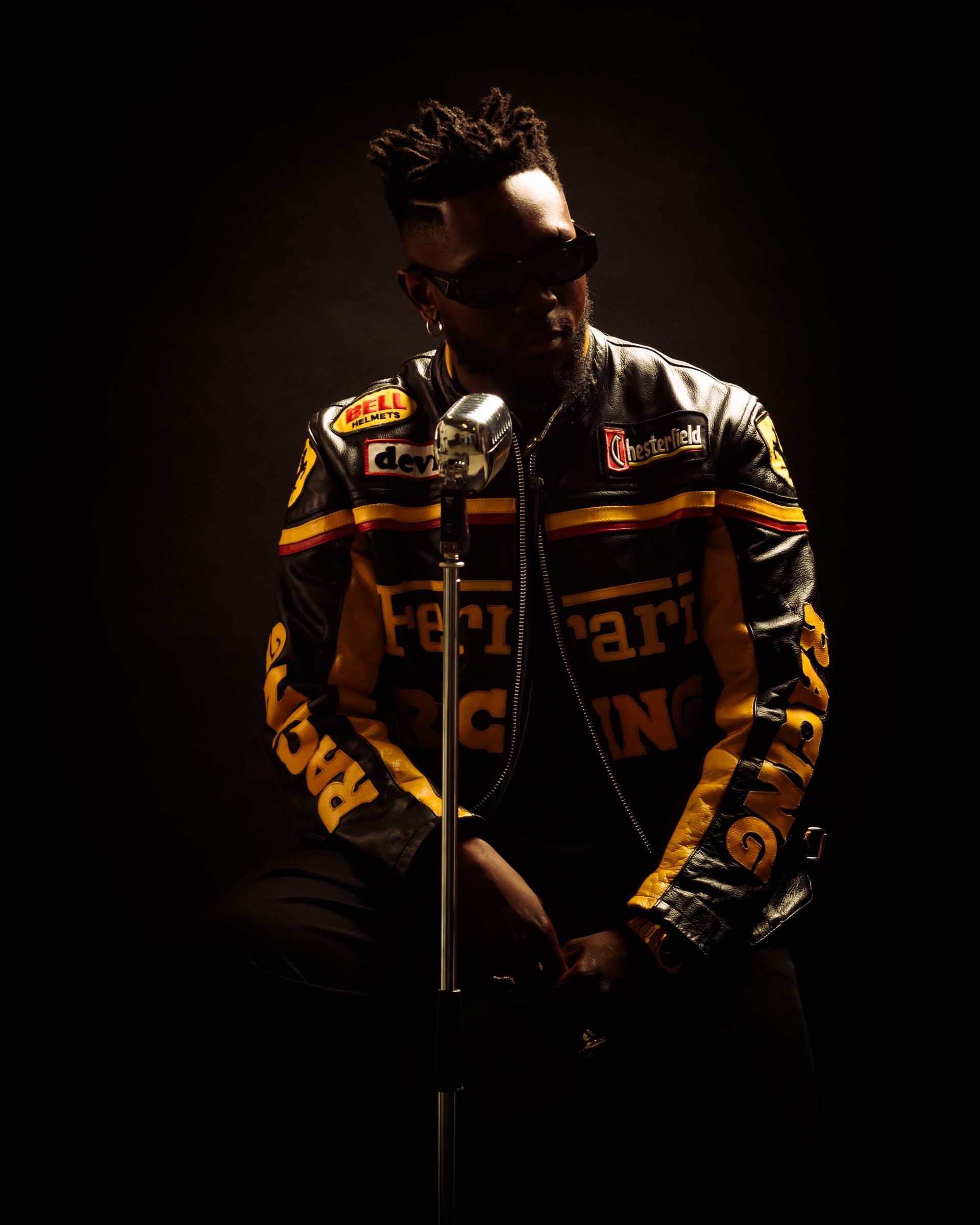 Microphone de studio au premier plan, ordinateur avec logiciel de montage audio visible en arrière-plan ; éclairage violet.