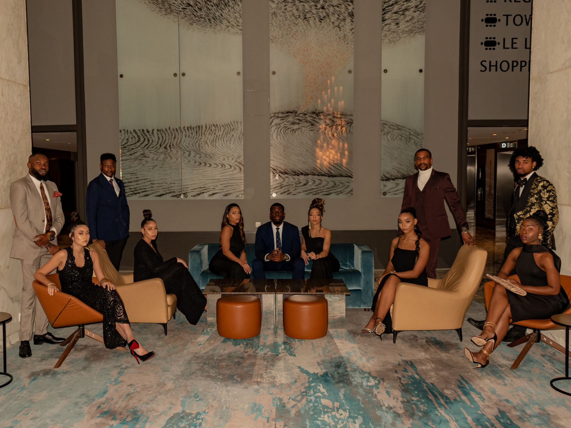 Groupe de personnes en tenue de soirée, posant dans un intérieur moderne aux tons neutres.