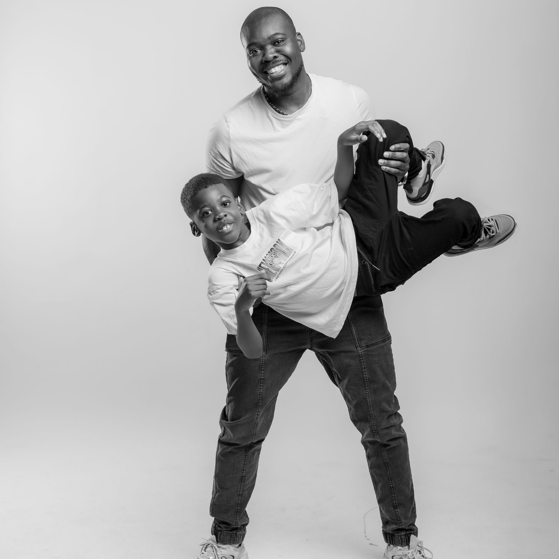 Un homme tenant un enfant, tous deux souriants, décor de studio.