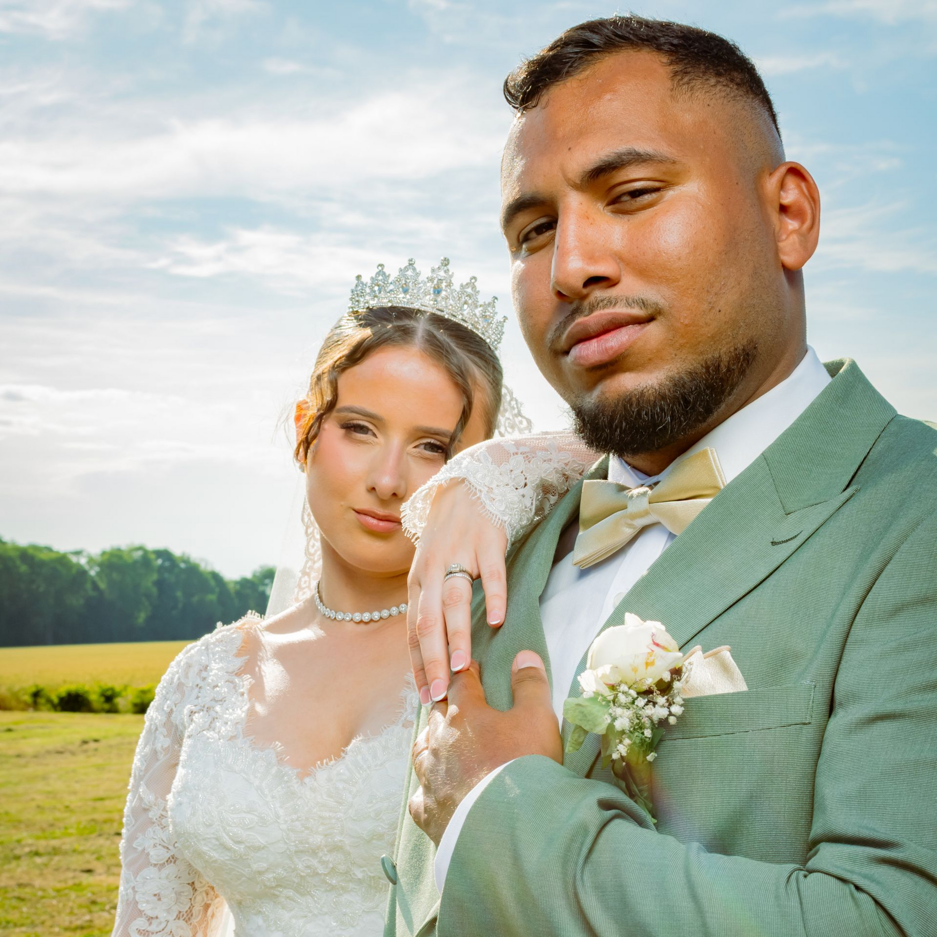 Les mariés s'enlacent, il l'embrasse sur la joue. Elle tient un bouquet.
