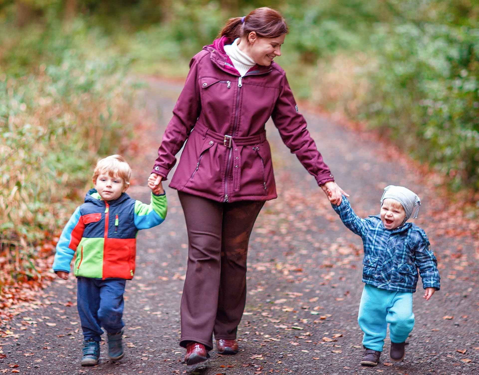 Une aide à domicile se promenant en forêt avec deux enfants