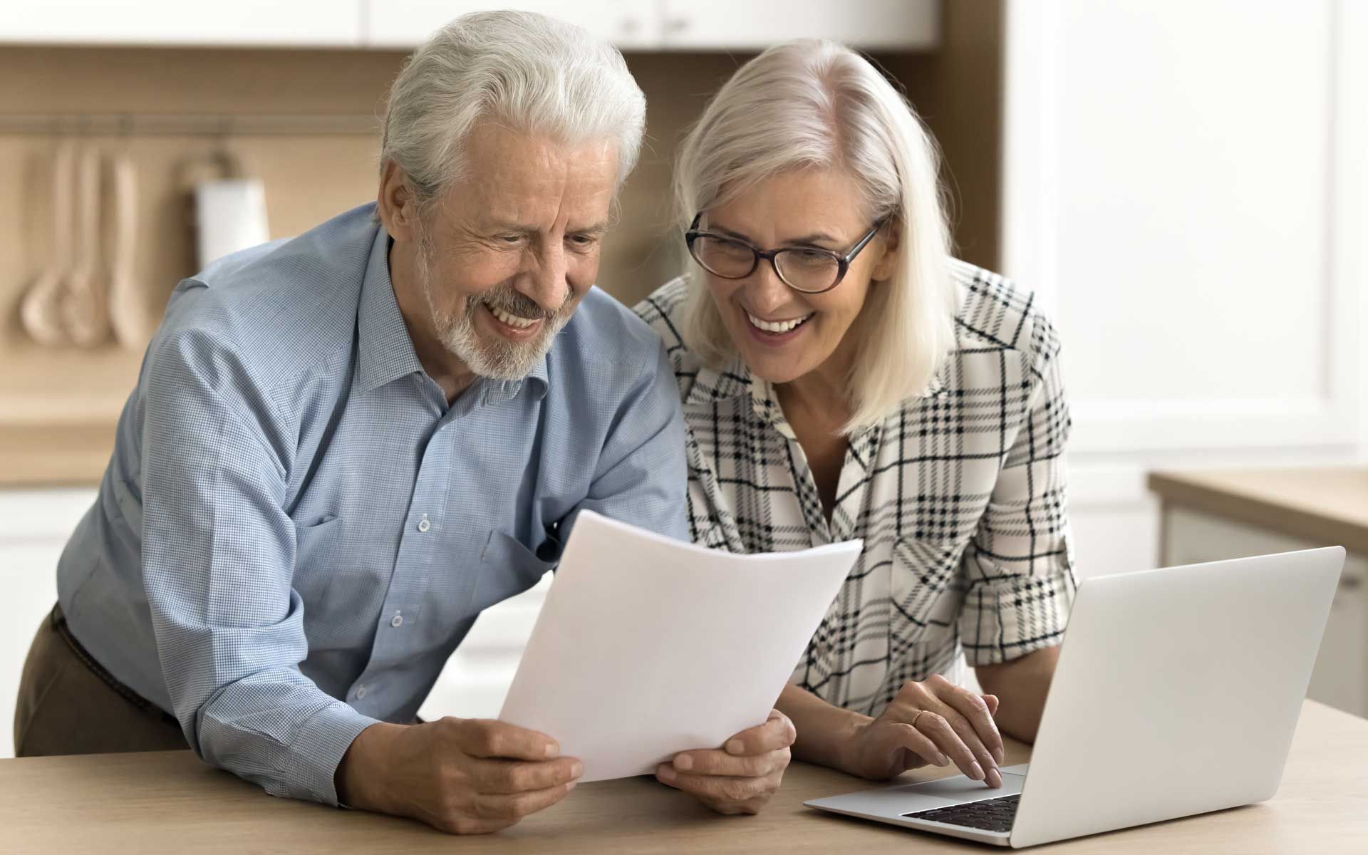 Un couple de personnes âgées heureux à la lecture d'un document