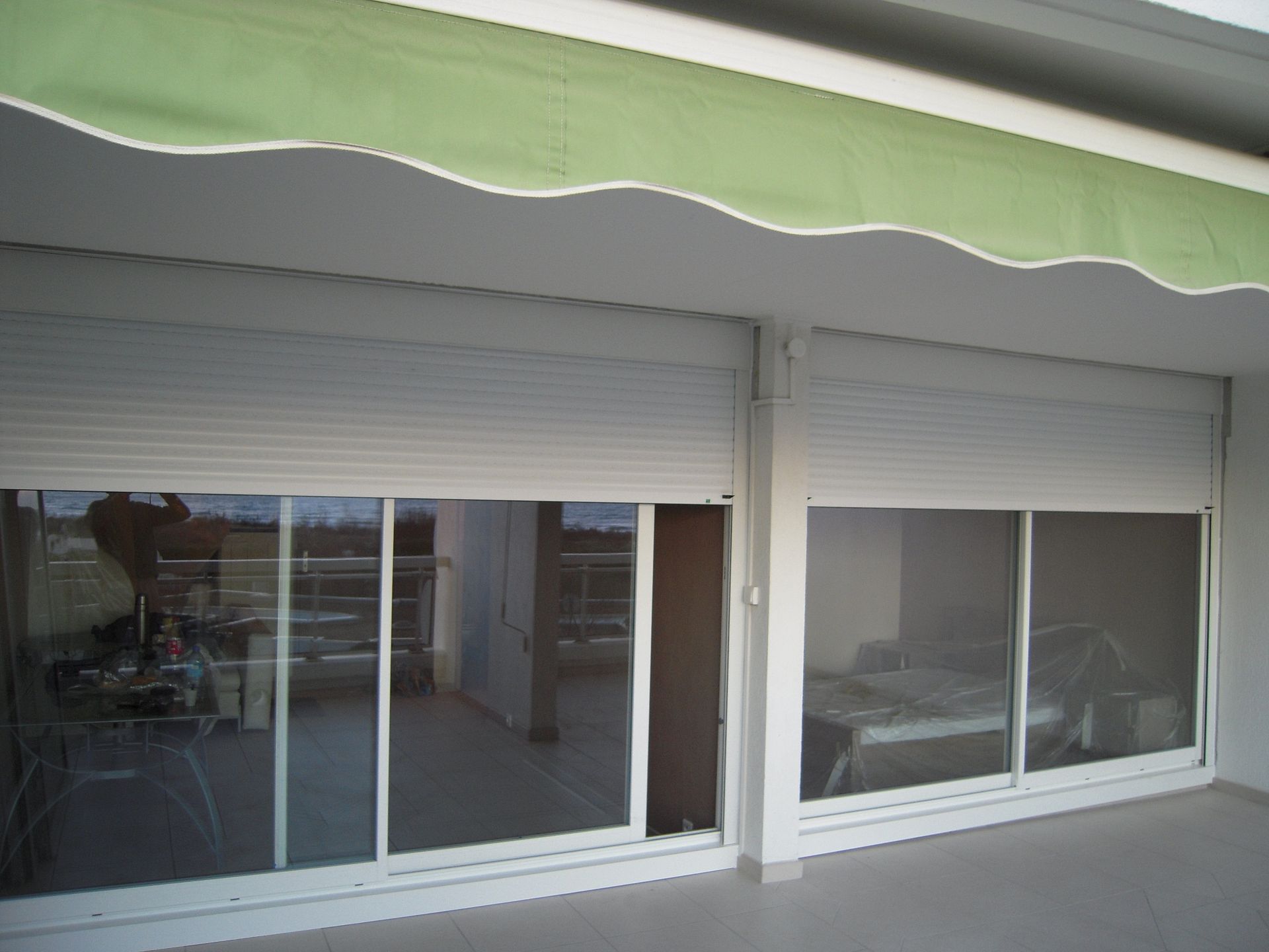 Baies vitrées donnant accès à une terrasse surmonté d'un store extérieur de couleur verte