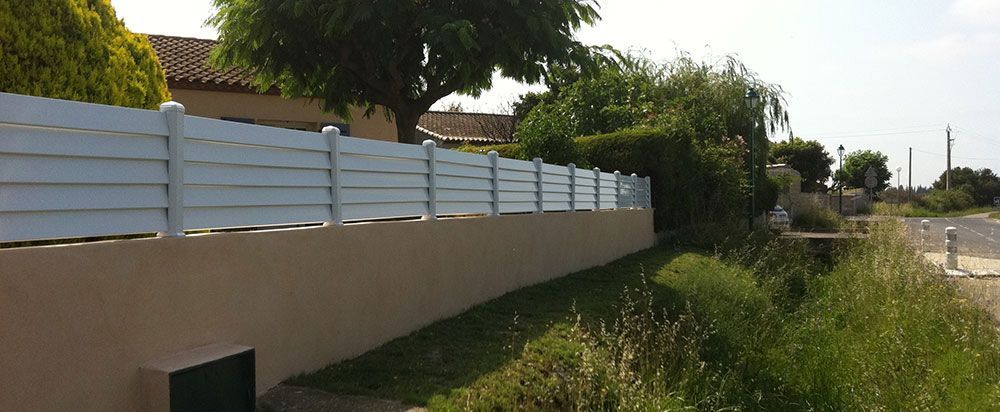 Clôture hybride avec une moitié en mur et l'autre moitié en latte de PVC blanc