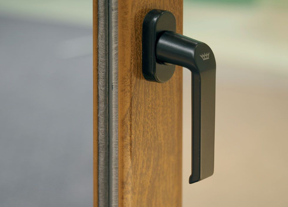 Gros plan sur la poignée noire d'une fenêtre en bois
