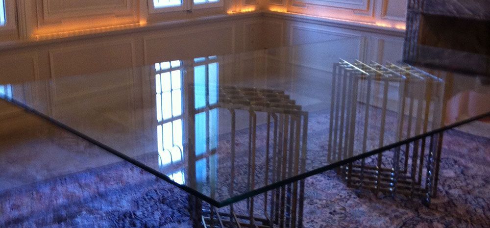 Table avec plateau en verre et pieds en fer forgé dans un salon