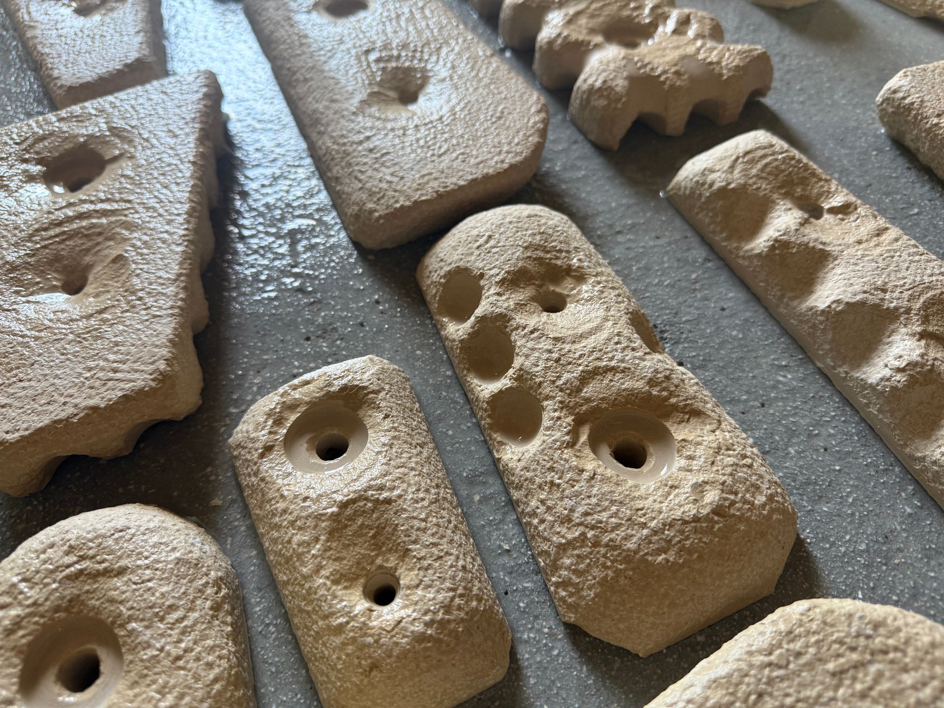Prise d'escalade en pierre couleur sable avec de grandes cavités arrondies sur un mur en bois.