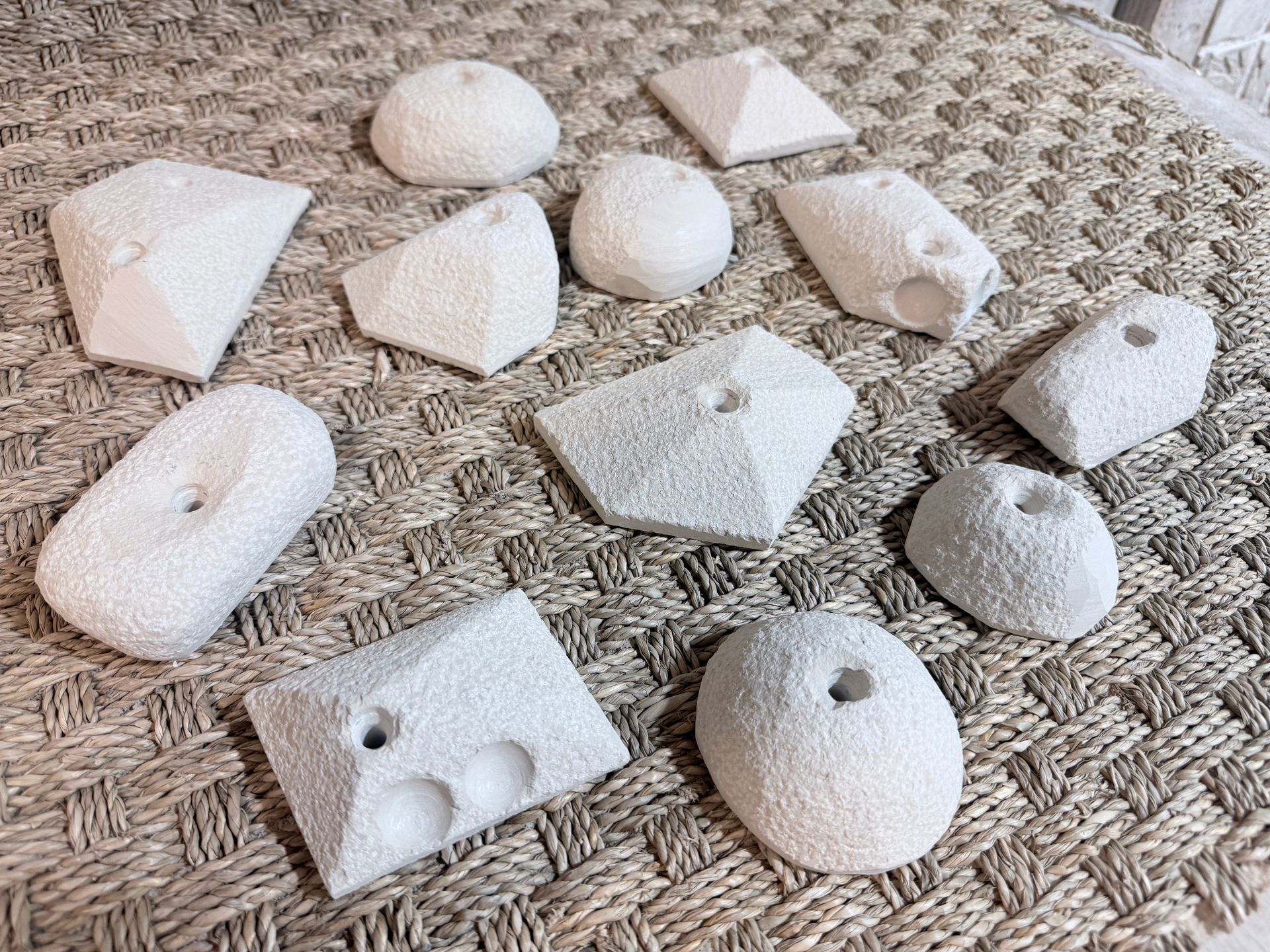 Prises d'escalade blanches et texturées sur un tapis tissé.