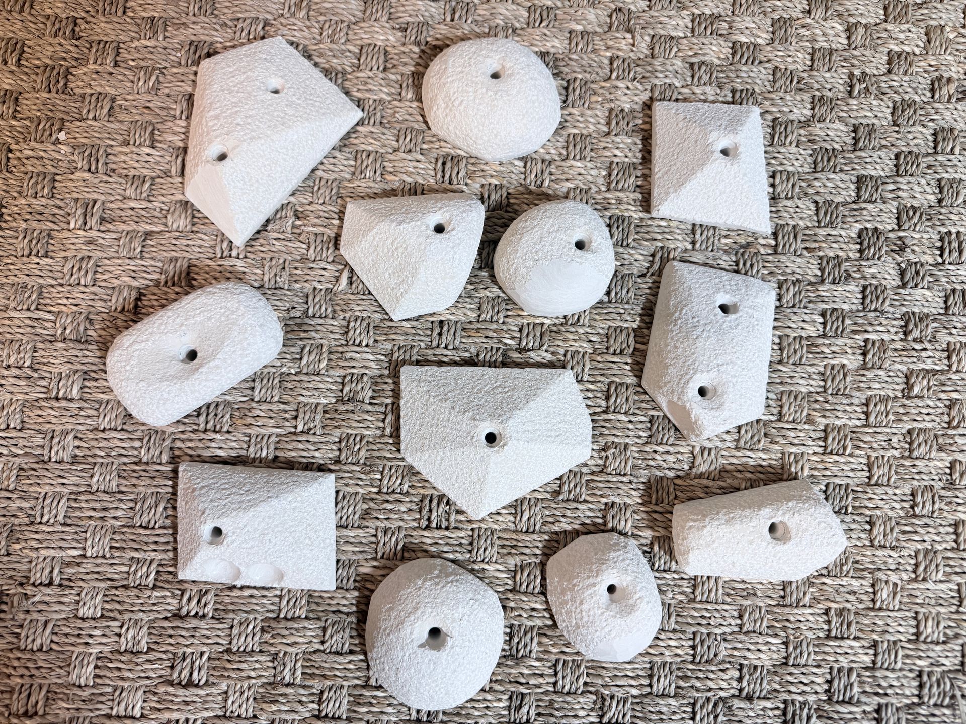 Prises d'escalade blanches de formes variées sur une surface brune texturée.