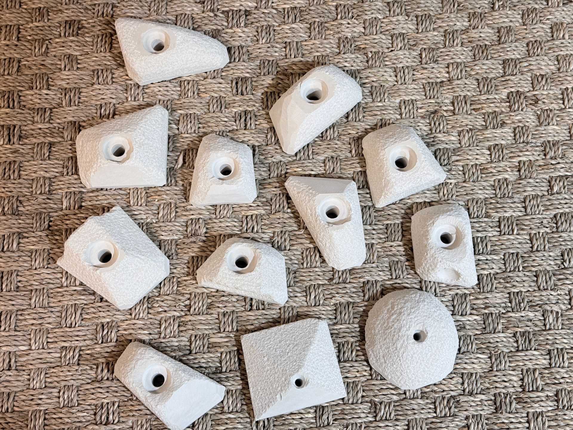 Prises d'escalade blanches à surfaces texturées, dispersées sur un tissu à motifs.