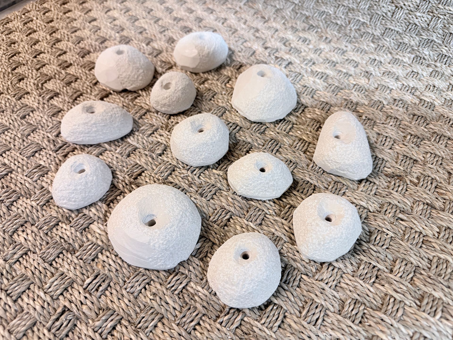 Coquilles d'oursins blancs sur une surface texturée brun clair. Tailles et formes variées.