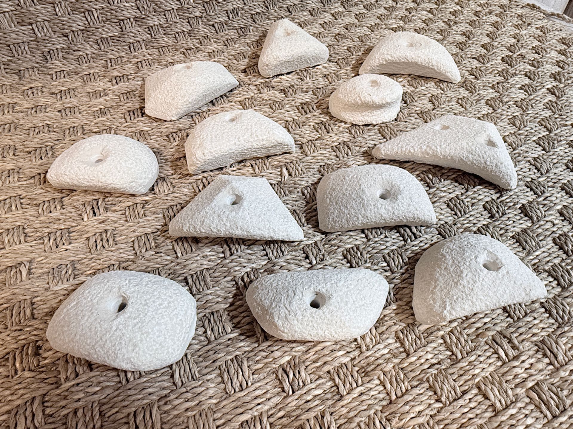 Prises d'escalade blanches dispersées sur une surface texturée brun clair.