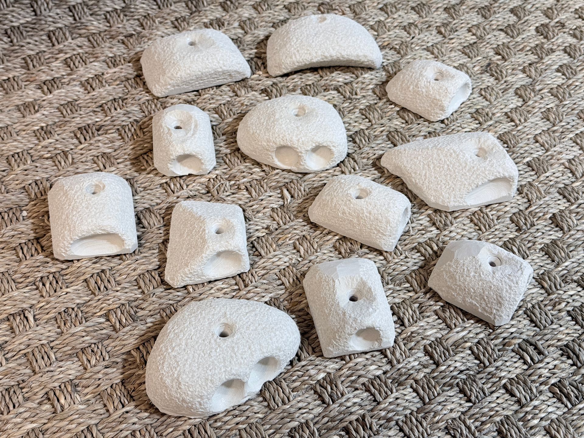 Prises d'escalade blanches sur une surface texturée de couleur neutre.