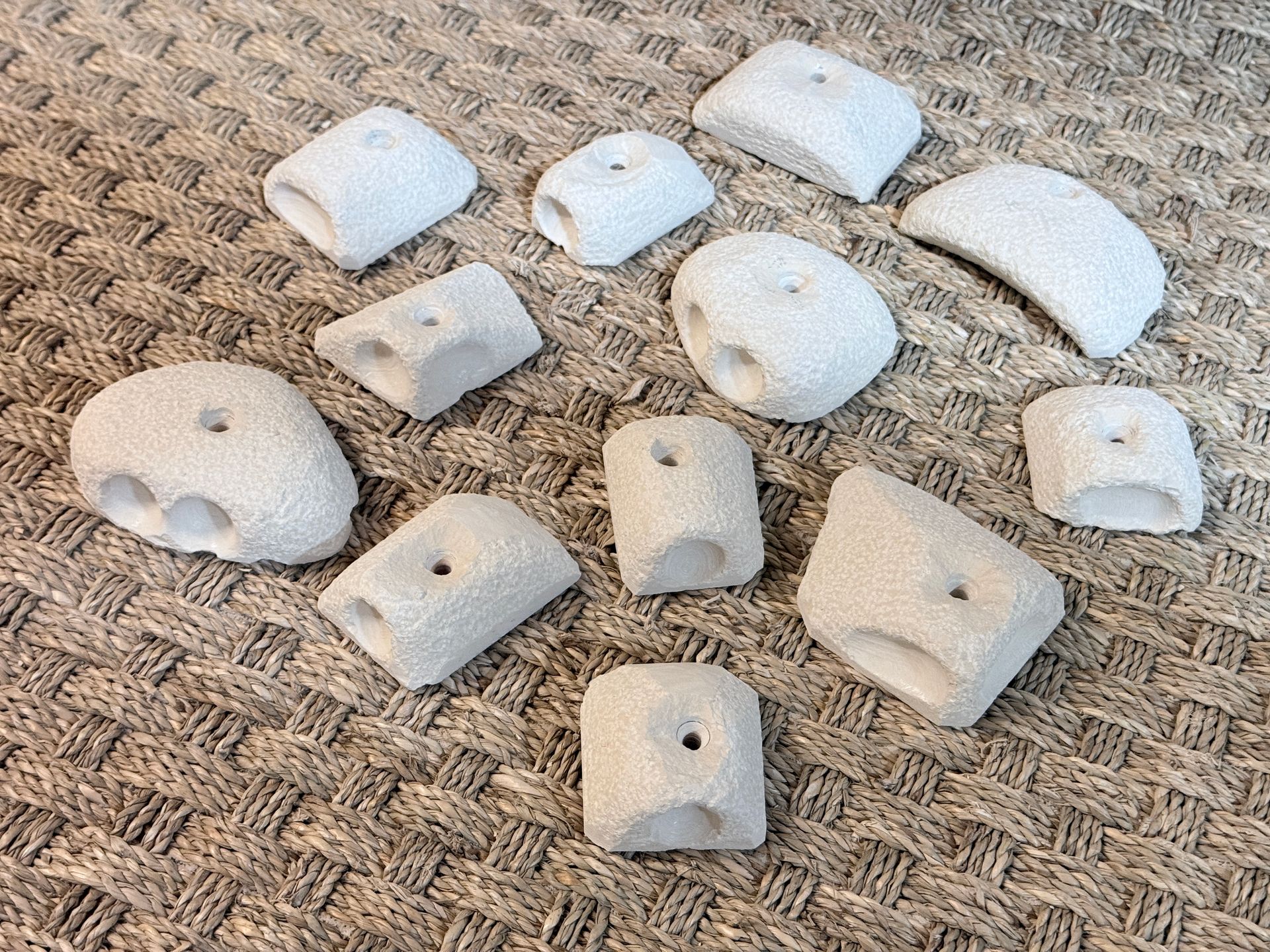 Prises d'escalade blanches dispersées sur une surface brune texturée.