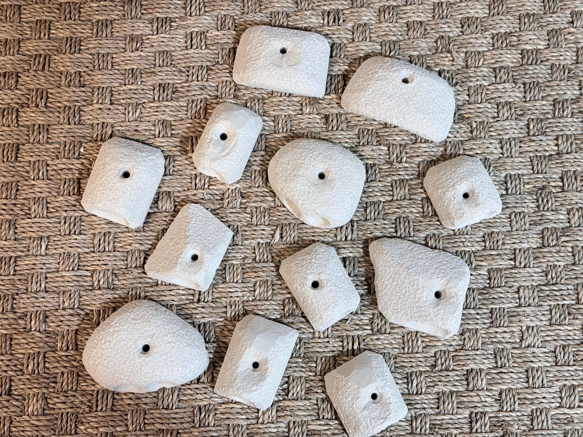 Prises d'escalade blanches disposées sur une surface texturée brune.