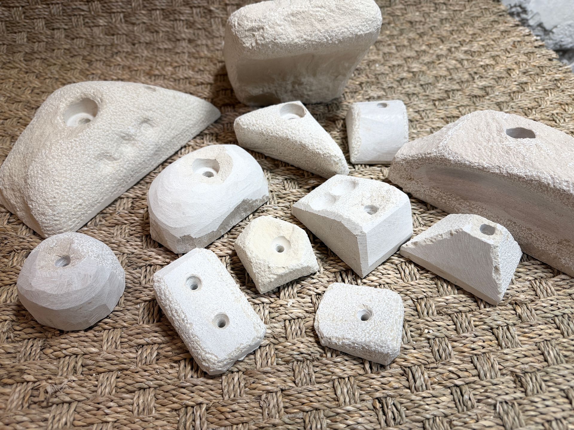 Assortiment de prises d'escalade blanches de formes et de tailles variées sur un tapis tissé