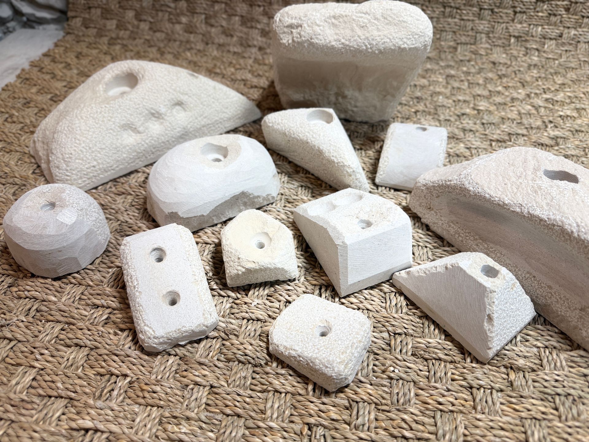 Prises d'escalade blanches de formes variées sur une surface brune texturée.