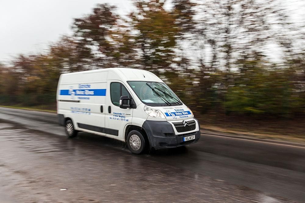Ein weißer Lieferwagen fährt eine Straße mit Bäumen im Hintergrund entlang