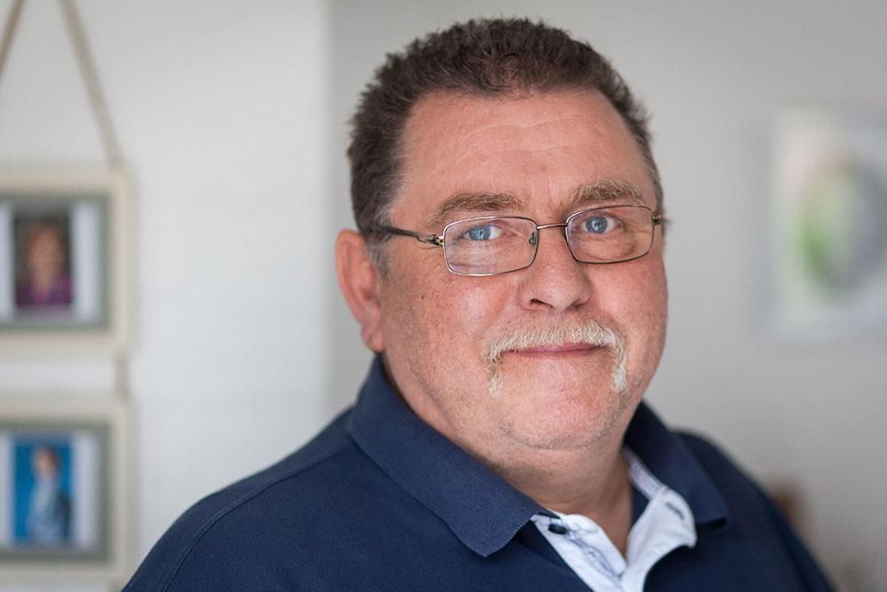 Ein Mann mit Brille und Schnurrbart schaut in die Kamera.