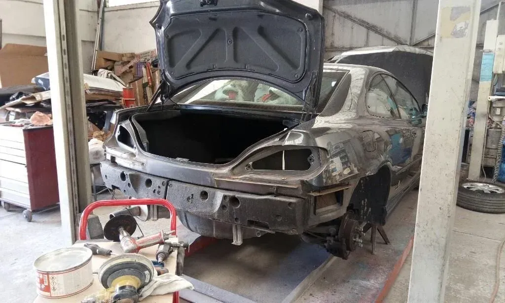 Une voiture grise à la carrosserie très abîmée