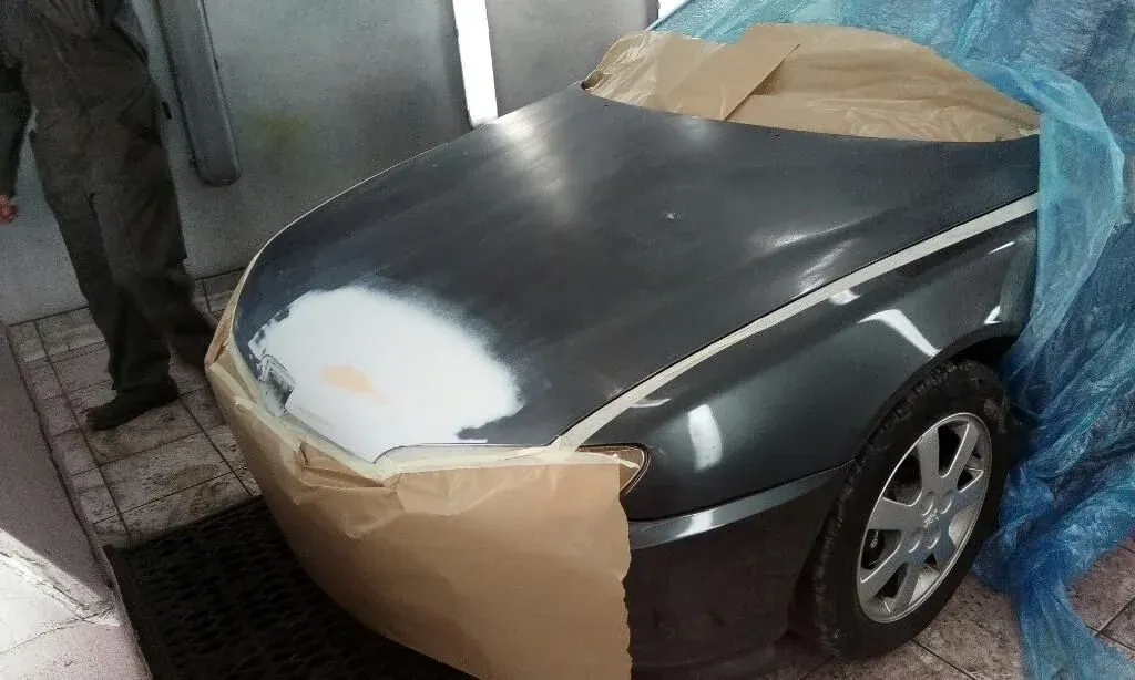 Le capot d'une voiture noire à la peinture abîmée