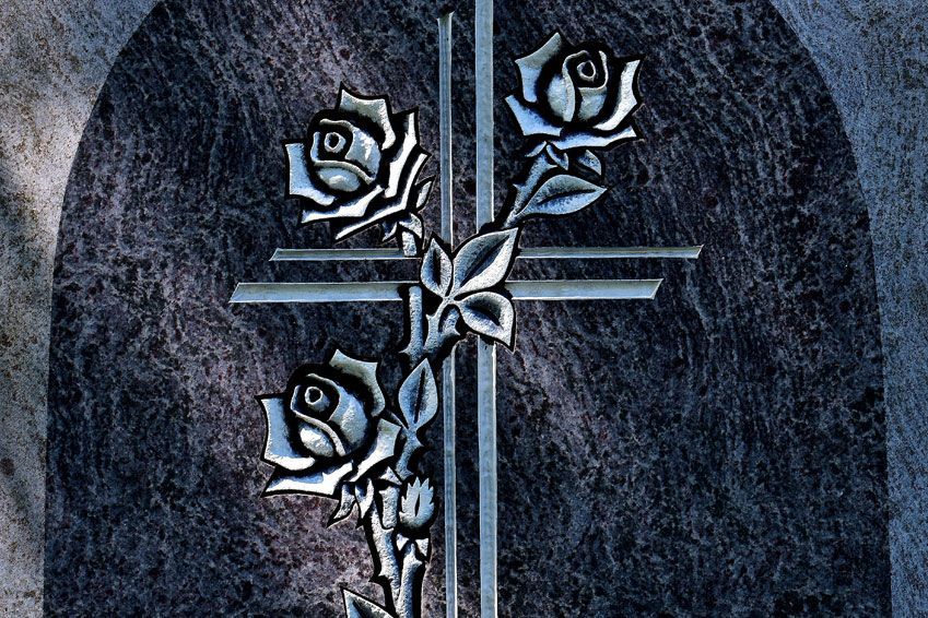 Ein Grabstein mit einem Kreuz und Rosen darauf