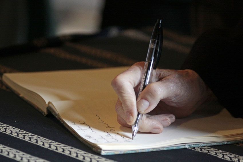 Eine Person schreibt mit einem Stift auf ein Stück Papier