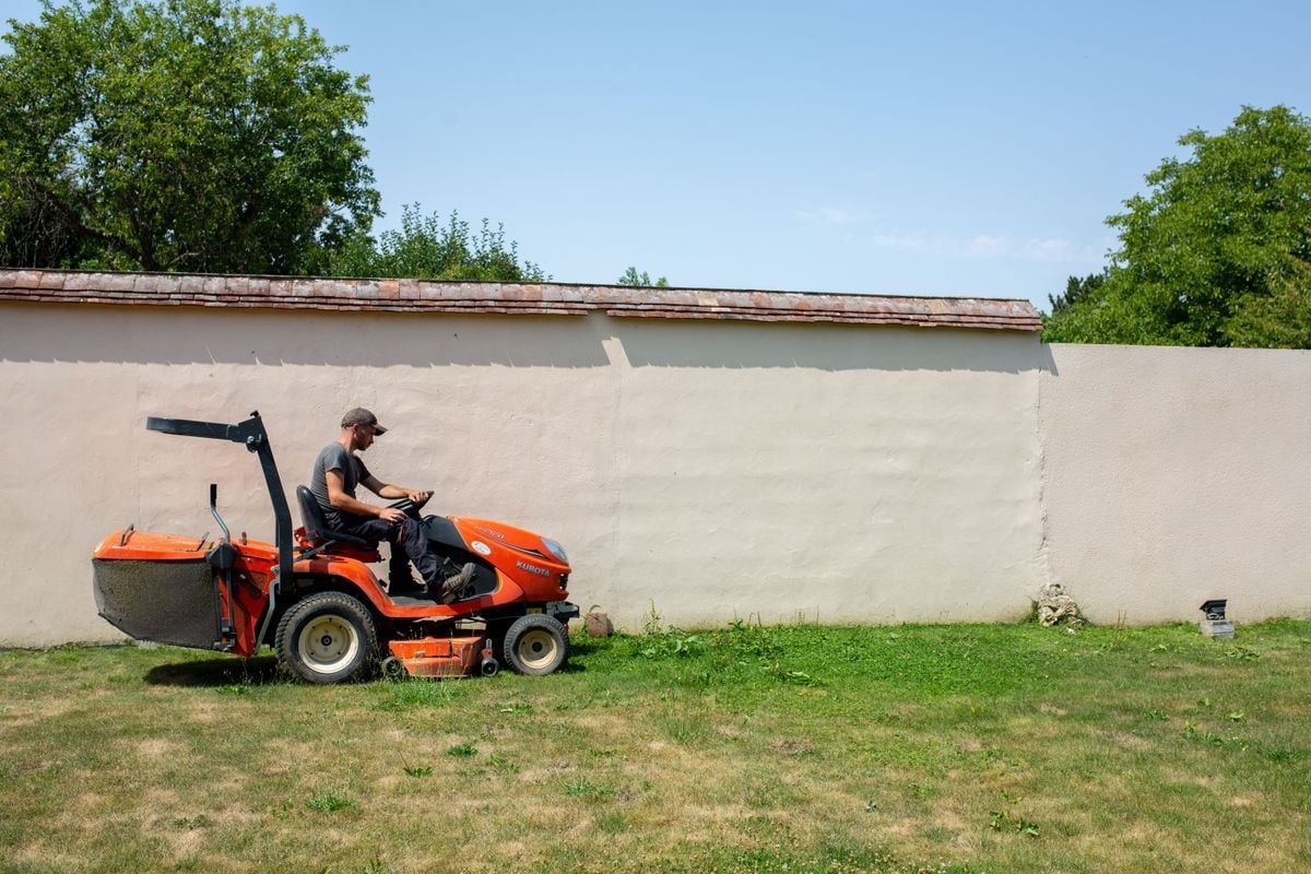 Homme sur une tondeuse autoportée rouge