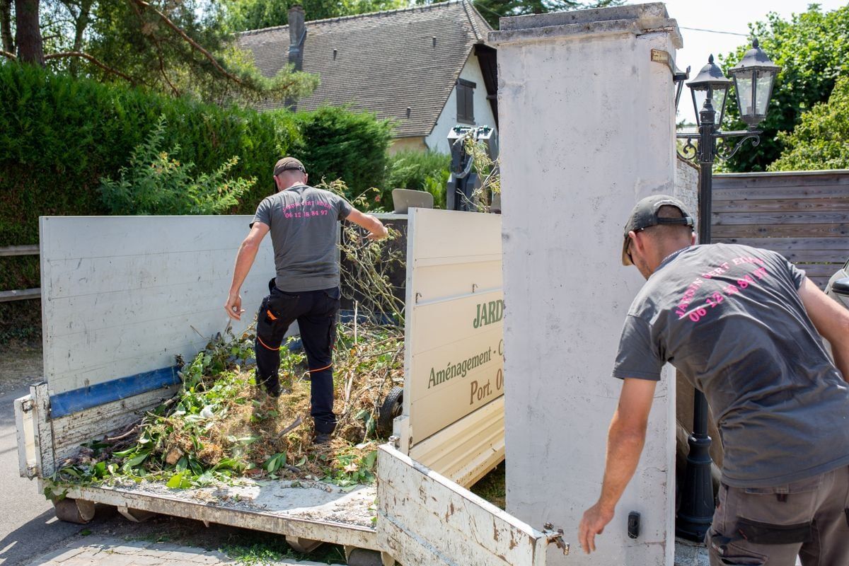Professionnels mettant des végétaux coupés dans une remorque Jardin Vert Eden après une intervention