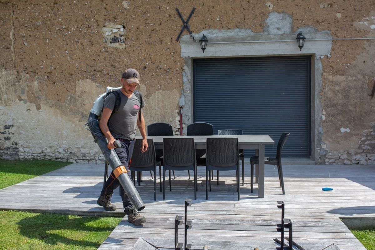Professionnel passant un souffleur sur une terrasse en bois
