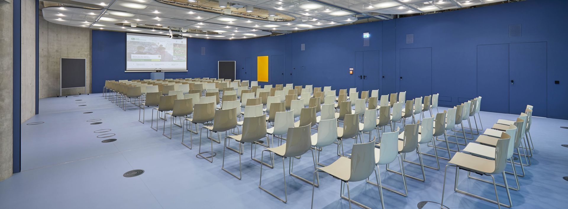 Ein Konferenzraum mit Stuhlreihen und einer Projektionsleinwand