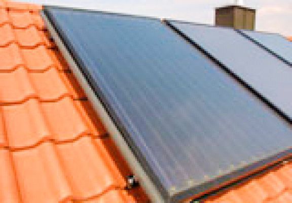 Un panel solar está situado encima de un techo de tejas rojas.