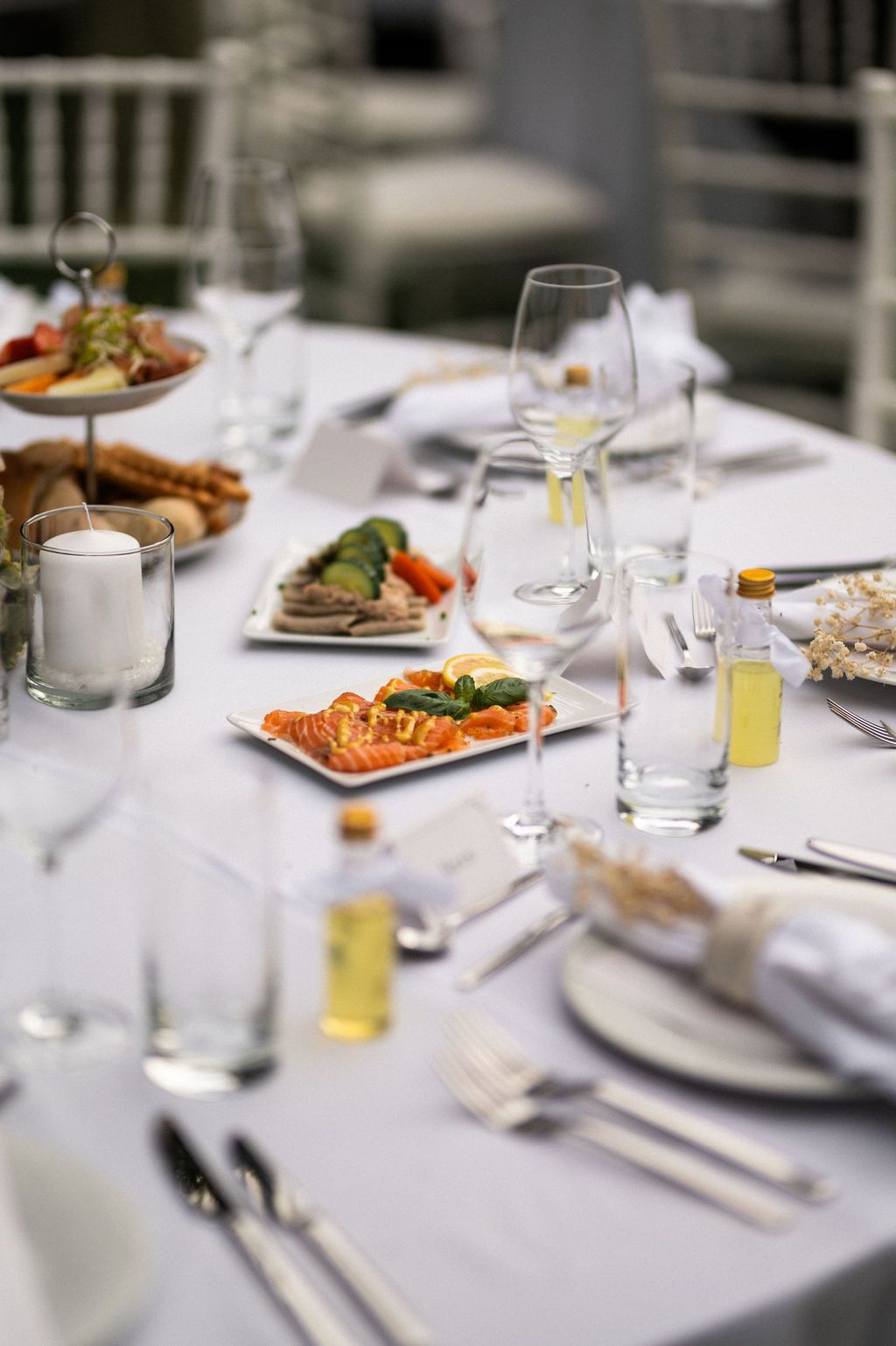 Formelles Tischgedeck mit Essen, Weingläsern und kleinen Ölflaschen.