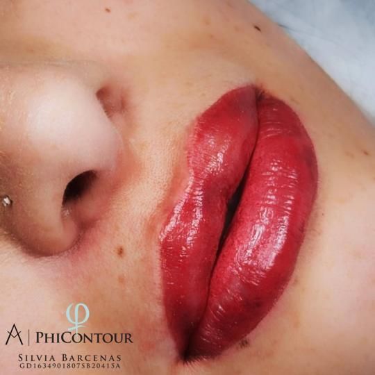 Primer plano de labios rojos recién tatuados con un logotipo PhiContour visible.