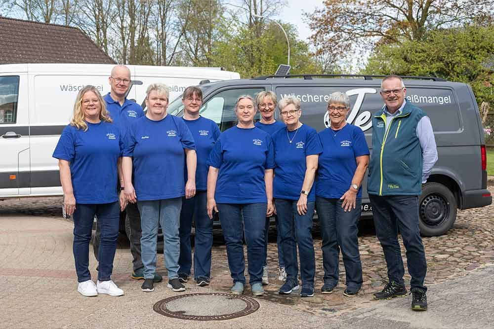 Eine Gruppe von Menschen posiert vor einem Lieferwagen für ein Foto.