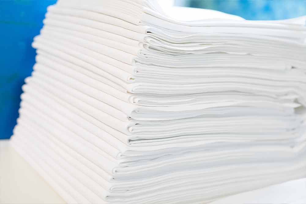 Ein Stapel weißer Handtücher liegt übereinander auf einem Tisch.