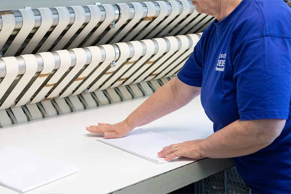 Eine Frau im blauen Hemd arbeitet an einer Maschine.