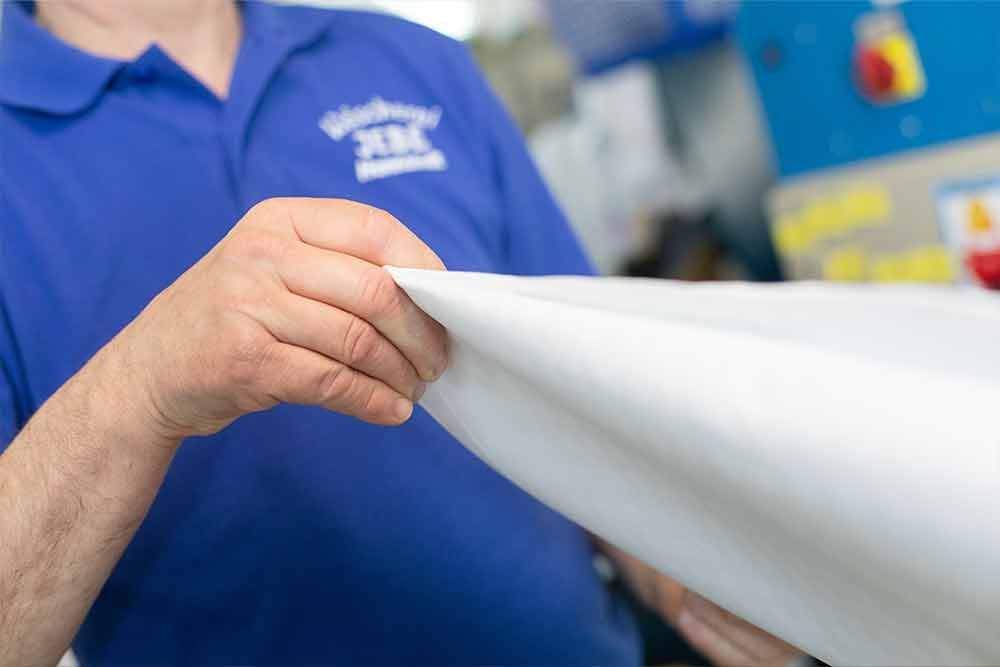 Ein Mann im blauen Hemd hält ein weißes Blatt Papier.