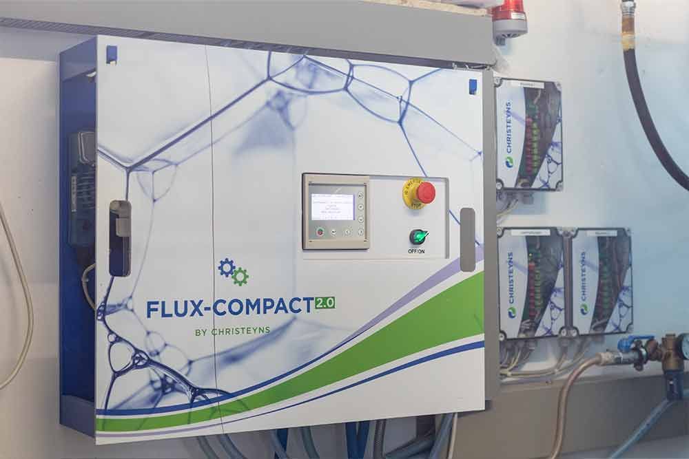 An einer Wand hängt ein Flux Compact-Bedienfeld.