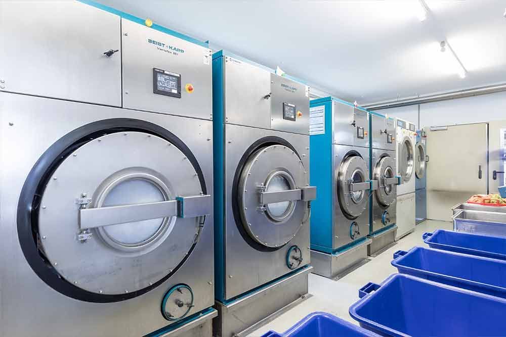 Eine Reihe von Waschmaschinen in einem Waschsalon mit blauen Tonnen.