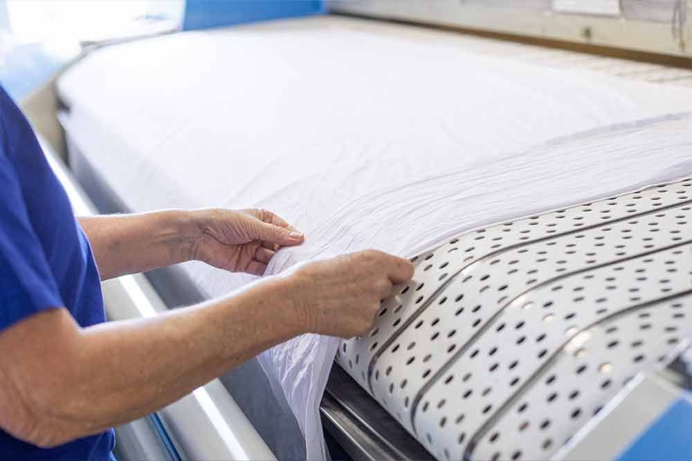 Eine Frau faltet Laken auf einer Maschine in einem Waschsalon.