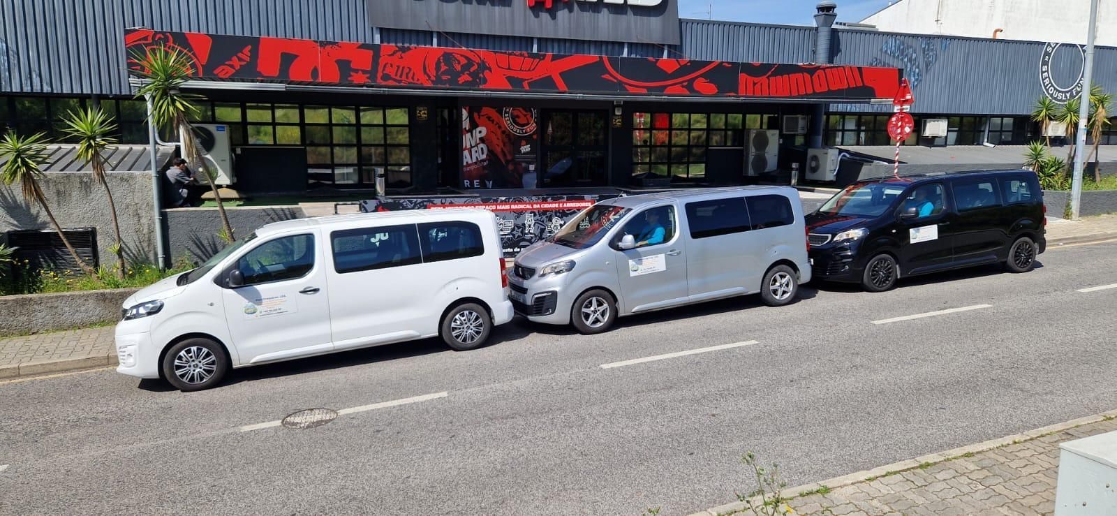 Três vans estacionadas em uma rua em frente a um prédio com sinalização vermelha.